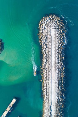 boat sailing near the breakwater of a harbor, top view from a drone clipart