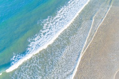 Deniz dalgalarının drone görüntüsü alacakaranlıkta sahilde kırılıyor, yaz tatilinde.