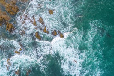 Dalgaların yukarıdan aşağı görüntüsü kayalara çarpıyor. Dalgalar kayalık kıyılara çarpıyor.