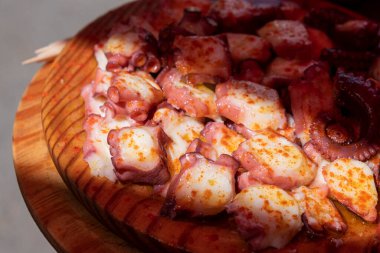 Ahtapot ahşap tabakta kırmızı biber ve zeytinyağıyla pişirilir. Galiçya yemeği, pulpo a feira