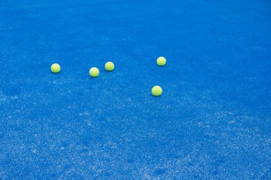 Seçici odaklanma. Sentetik çimenli mavi raket tenis kortu ve birkaç sarı top.