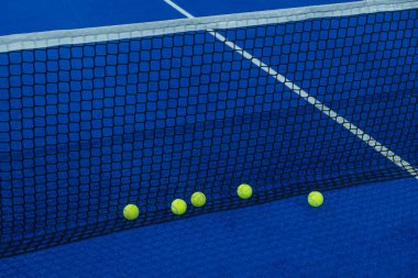 Mavi raket tenis kortunun ağındaki çoklu toplar..