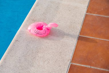 Yüzme havuzunun kenarında sönmüş küçük pembe flamingo.