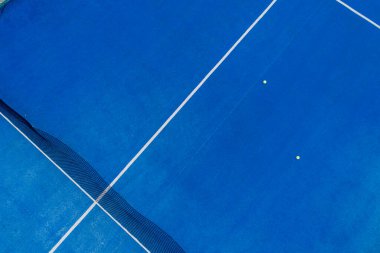 Yüzeyinde toplar olan mavi raket tenis kortunun hava aracı görüntüsü