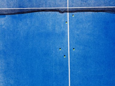 Yüzeyinde birkaç top, raket spor arka planı olan bir tenis kortunun havadan görünüşü