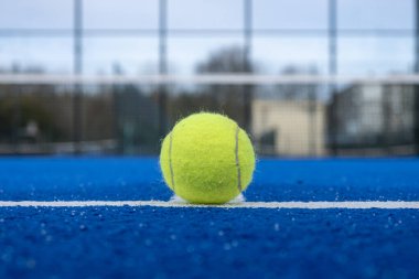 Mavi raket tenis kortunun taban çizgisinde bir top, raket sporu konsepti