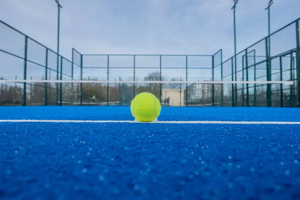 Mavi bir raket tenis kortunun taban çizgisinde bir topu görmek