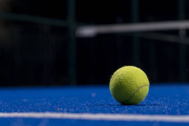 Geceleri mavi bir raket tenis kortunun yüzeyinde iki top