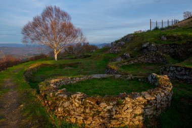 Remains of the houses of the hillfort of Castromao, Celanova. At sunset clipart