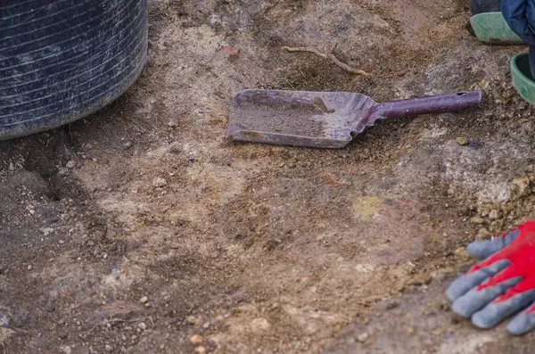 Seçici odak, kırmızı eldiveni, kömür yığını ve sepeti olan bir arkeologun bulanık eli. Çalışma araçları