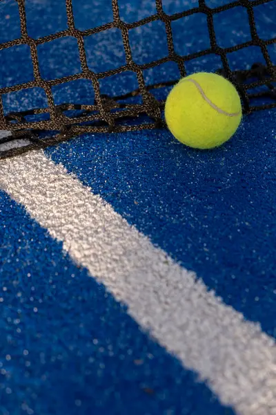 paddle tennis ball in the net of a blue paddle tennis court. Racket sport courts