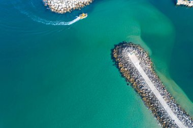 Limana giren bir balıkçı teknesi dalgakıran ve turkuaz suyla korunuyor. Drone fotoğrafçılığı