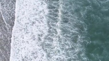 Bir kumsalda dalgaların kırılışının yukarı doğru görüntüsü. Üst görüntü görüntüleri