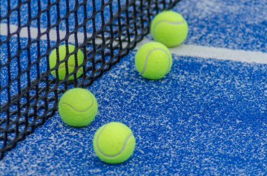 net of a blue paddle tennis court and five balls, racket sports concept clipart