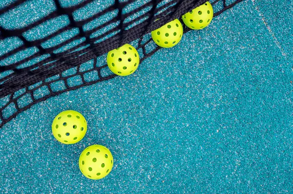 Mavi bir picleball sahası ve beş top.