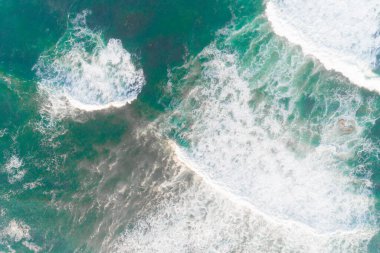 Kumsalın yakınında dalgalar köpürüyor, bir drondan görülen turkuaz deniz. Hava görünümü