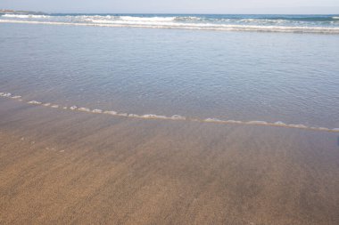 Şafak vakti bir kumsalın kıyısında gelgitte