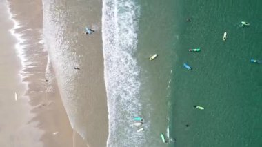 İnsanların sörf yapmayı, su sporları kavramını öğrendiği bir plajın insansız hava aracı videosu.