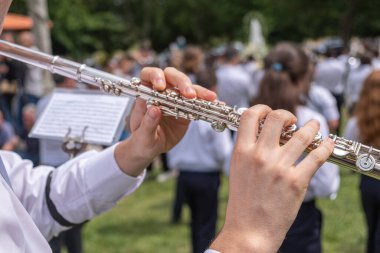 Açık hava konserinde flüt çalan bir müzisyenin ellerinin yakın çekimi.
