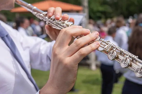 close-up view of a musician\'s hands playing a transverse flute at an outdoor event