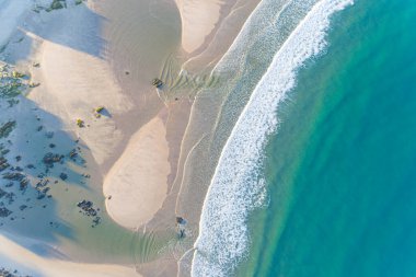 Zenital hava aracı turkuaz renkli suyu olan bir sahilin görüntüsü.