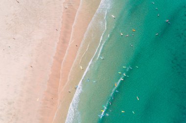 Sabahın erken saatlerinde sahildeki bir sörf okulunun öğrencileri az sayıda insanla, insansız hava aracı ile gökyüzü manzarası.