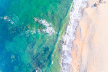 Şafak vakti boş bir plajın kıyısında, turkuaz su. İnsansız hava aracı ile hava üstü görünümü