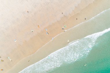 Sabahın erken saatlerinde kumsaldaki bir sörf okulunun öğrencileri birkaç kişiyle hava zenitali bir hava aracıyla.