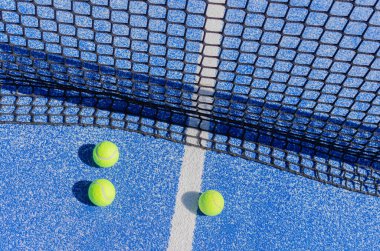 Mavi raket tenis kortunun yanında üç top, raket spor konsepti.