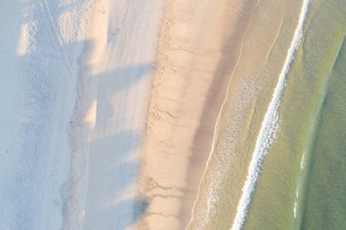 Yazın gündoğumunda bir kumsalın kıyısı. İHA 'dan görülebildiği gibi. Görüntünün tam üstünde. Yaz doğa manzarası.