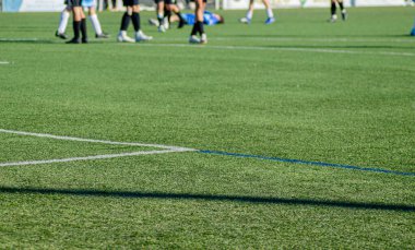 Futbol sahası, arka planda odak dışı bir oyuncu diğer oyuncuların bacaklarının arasında yerde yatıyor..