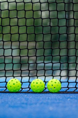 Picleball sahasının yanındaki ağaçtan yeşil toplar.