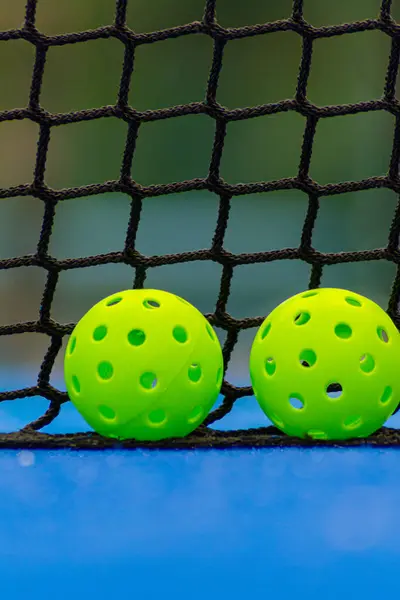 Pickleball sahasının yanında iki yeşil picleball topu, yeni raket sporu