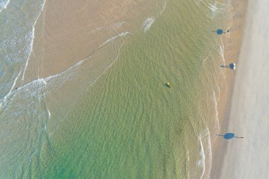 Sahilde sörf tahtaları olan dört sörfçünün hava aracı görüntüsü.