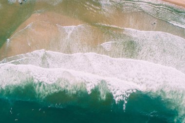 Güneşli kıyı şeridine çarpan yaz dalgalarının hava aracı görüntüsü