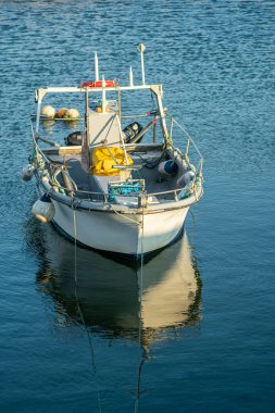 Yazın sakin liman sularına yansıyan küçük balıkçı teknesi
