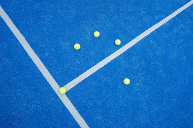 Mavi raket tenis kortunun üst görüntüsü ve dokusu ve beş sarı top. Yapay çim raket sahası.