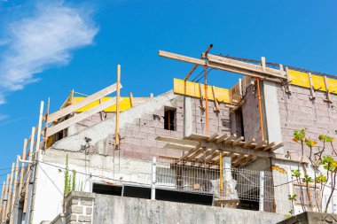 Mavi gökyüzü gününde yapım aşamasındaki bir evin tavan arası manzarası