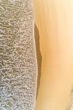 Yazın günbatımında kumlu bir kumsalın kumlu sahilinin zenital hava aracı görüntüsü