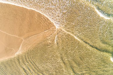 Zenital hava aracı yaz mevsiminde bir sahil kıyısında dalgaların akışını gösteriyor.