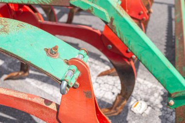 Paslanma belirtileriyle kırmızı ve yeşil bir sabanın yakın görüntüsü