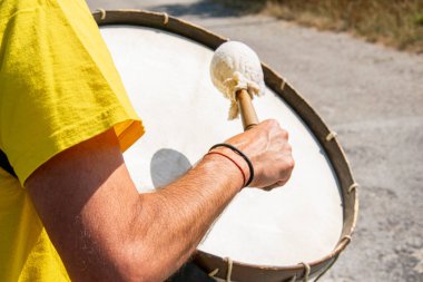 Sarı tişörtlü bir adamın kolu bas davul çalıyor.