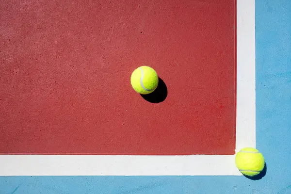 Mavi ve kırmızı tenis kortunda iki tenis topunun üst görüntüsü