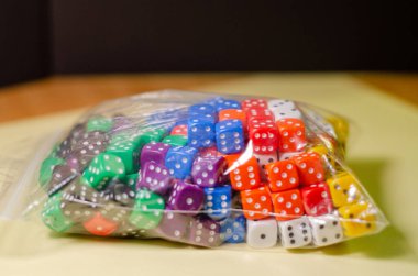 six-sided dice of various colors in a plastic bag clipart