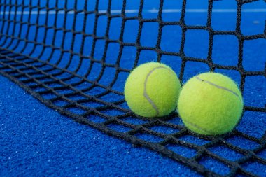 Mavi raket tenis kortu ağı ve iki top. Raket sporları konsepti.