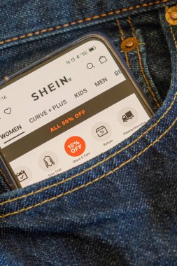 Bir kot pantolonun ön cebinde akıllı telefon, ekran Shein uygulamasında.