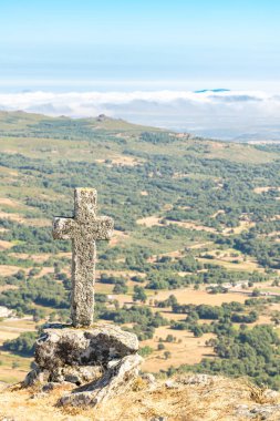 Galiçya 'nın iç kesimlerindeki bir vadinin manzarası, bir dağın tepesinden bir taş haçla görülüyor..