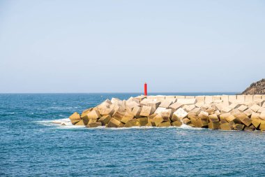 Beyaz beton küplerden yapılmış bir dalgakıran ve Puerto de Vega limanının girişinde bir işaret. Asturias, İspanya.