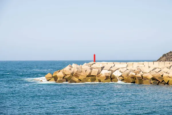Beyaz beton küplerden yapılmış bir dalgakıran ve Puerto de Vega limanının girişinde bir işaret. Asturias, İspanya.