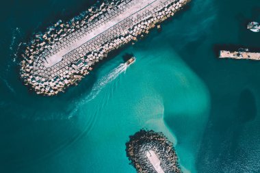 Bir balıkçı teknesi bir limanın dalgakıranına giriyor, İHA 'nın üst görüntüsü.